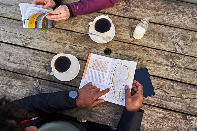Open guidebook on table with cups of coffee