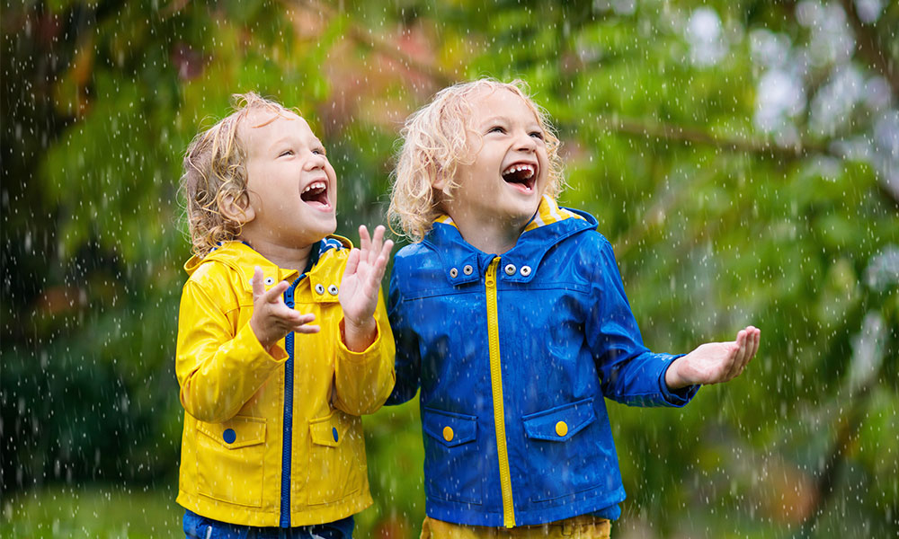Two children laughing in the rain