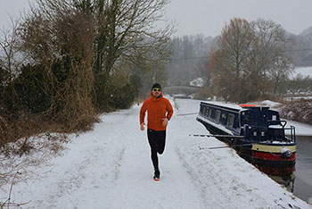 Man running in snow by a canal