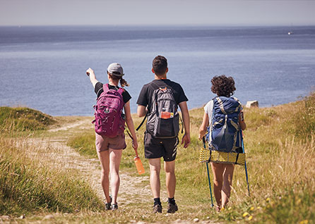 3 people walking in a field on the coast