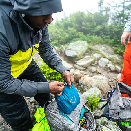 Man packing stuff into osprey dry pack
