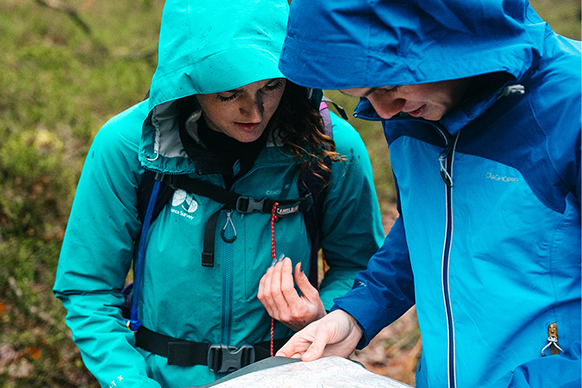 Two people in raincoast looking at Ordnance Survey map